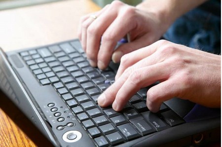 Si vedono la tastiera di un pc e le mani di un redattore on line